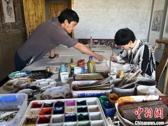 圖為2020年8月下旬，敦煌“80后”畫家張杰龍(左)在為云南麗江“學(xué)生”莫北講解敦煌壁畫的繪畫技巧。　馮志軍 攝
