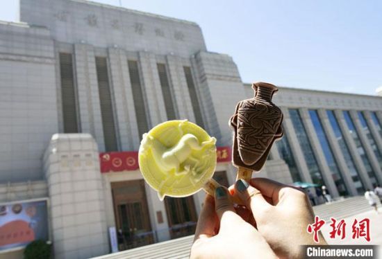 2021年7月30日，游客手拿“銅奔馬”“彩陶瓶”造型的雪糕，在甘肅省博物館前拍照打卡?！「哒?攝