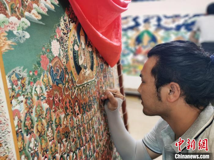 圖為更登才讓的徒弟繪畫唐卡?！?zhí)砀?攝