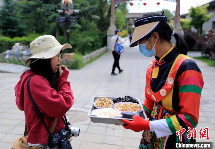 圖為身穿土族服飾的女性介紹當(dāng)?shù)靥厣〕??！⊙Φ?攝