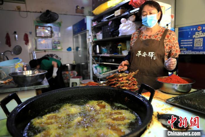 圖為平安驛·河湟民俗文化體驗地內(nèi)的商戶炸干板魚?！⊙Φ?攝