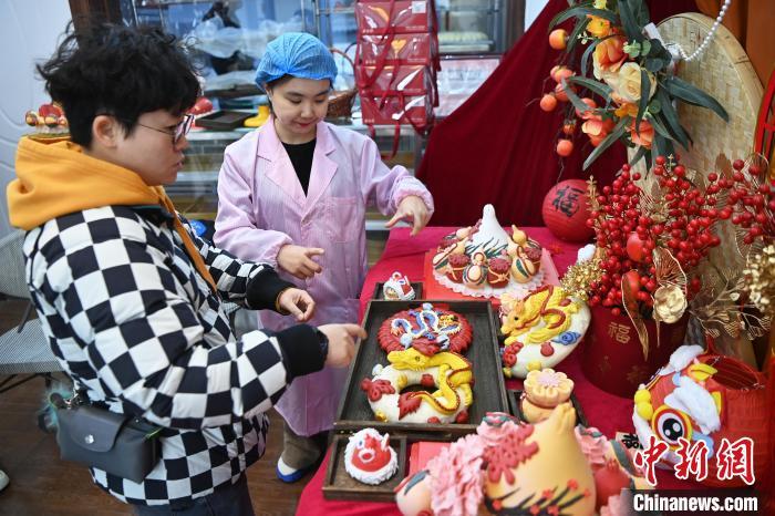 1月25日，隨著春節(jié)臨近，蘭州一花饃店“龍”元素花饃熱銷。圖為工作人員向顧客推薦“龍”元素花饃。九美旦增 攝</p><p>