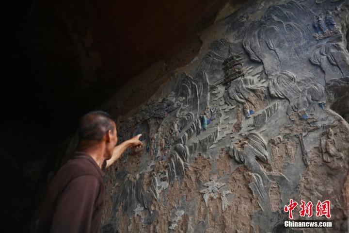 7月15日，甘肅省平?jīng)鍪袥艽h百里石窟長廊羅漢洞石窟內(nèi)，該窟文保員郭建平介紹窟內(nèi)石刻彩繪壁畫。郭建平家中三代人曾自發(fā)保護(hù)羅漢洞石窟。羅漢洞石窟遺存40余個(gè)窟龕，以北魏至清代風(fēng)格為主。中新社記者 李亞龍 攝