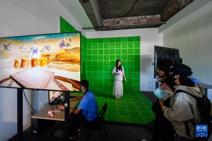 7月22日，游客體驗(yàn)“尋境敦煌——數(shù)字敦煌沉浸展”后，在虛擬演播廳拍攝一段真人與洞窟虛擬場景交互的視頻。新華社記者 郎兵兵 攝</p>
<p>